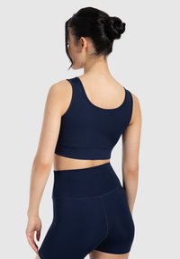 Top corto atlético en azul marino y pantalones cortos de talle alto hechos de una tela suave y elástica, con un diseño clásico sin patrones ni acentos.