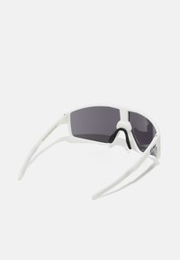 Weiße Sportsonnenbrille mit dunkelgrauen getönten Linsen, einem umschließenden Design und dünnen, flexiblen Bügeln. Mit einem gummierten Nasenpolster für zusätzlichen Komfort.
