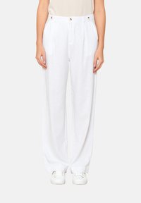 White linen wide-leg pants with a high waist, featuring front pleats and decorative button accents. Paired with white sneakers.