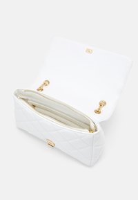 Bolso acolchado blanco con hardware dorado. Presenta un interior con cremallera, dos compartimentos y un cierre con solapa. Acabado en cuero texturizado.