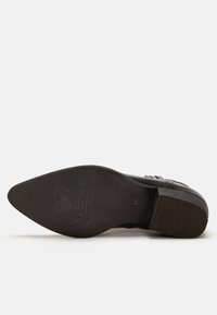 Zapato de cuero negro con punta afilada y tacón bajo. La suela de goma presenta un patrón texturizado. En el interior tiene el logo de la marca en relieve, talla 37.