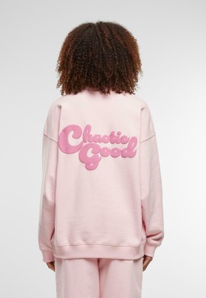Roosat sweatshirdid, mille taga on suured "Kaootiline Hea" tekstid julgete, mullilaadsete kujunditega. Pehme kangas, lõdva kärbse ja soonikkääridega.