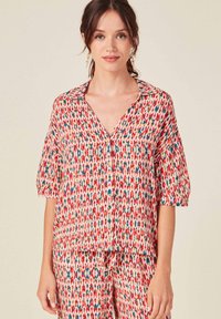 Camisa de botones roja y blanca con mangas cortas que presenta un patrón abstracto multicolor y un corte relajado, confeccionada en una tela ligera.