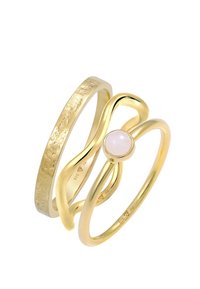 Set aus drei goldenen Ringen mit einem glatten, verdrehten Design und einem zentralen Ring mit einem blassen rosa Stein. Strukturelle Akzente auf einem Band.
