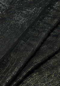 Tessuto intrecciato nero con fili metallici, creando una finitura texturizzata. I bordi presentano un sottile dettaglio sfilacciato, che arricchisce il design.