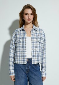 Witte en blauwe geruite jas met voorzakken, knoopsluiting en een kraaghalslijn. Zachte stof met een gestructureerde afwerking.