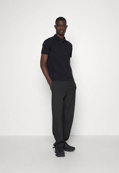 Marine blå polo skjorte med korte ermer, sammen med mørkegrå skreddersydde bukser og svarte joggesko, med et enkelt, klassisk design.