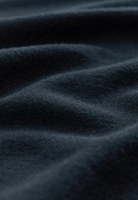 Țesătură de culoare albastru închis cu o textură netedă și moale; prezintă ondulații subtile și un model fin de tricot.