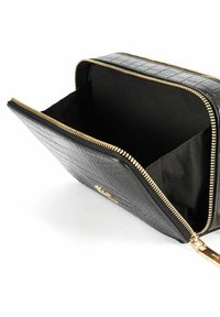 Czarna torba z fakturowanej ekologicznej skóry z złotym zamkiem. Wnętrze to czysta tkanina w kolorze czarnym, z jedną pojemną komorą i bez dodatkowych kieszeni.