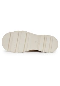 Suela de zapato beige claro con una superficie de goma texturizada, que presenta ranuras horizontales y un diseño de punta redondeada.