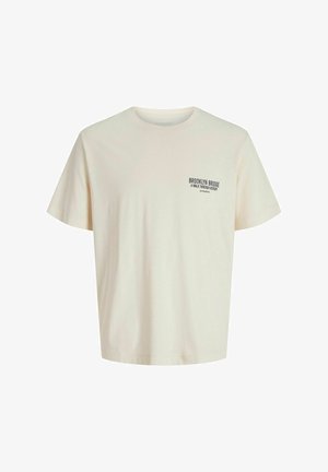 T-shirt a maniche corte di colore crema, realizzata in cotone, con colletto rotondo e testo nero nella parte superiore sinistra del petto.