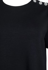 Black short-sleeve top with round neckline featuring three decorative flower-like accents in silver at the shoulder. Soft, smooth fabric texture.