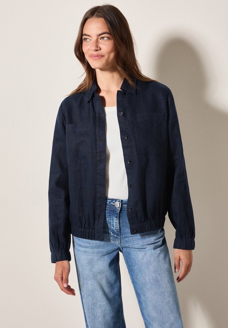 Marineblauwe button-up jas met een ontspannen pasvorm, elastische boorden en tailleband, met een subtiele textuur en een enkele borstzak.