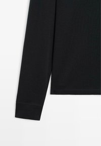 Schwarzes Langarmshirt mit rundem Ausschnitt, aus weichem Baumwollmaterial, und mit einem genähten Saum sowie einem taillierten Bündchen-Detail.