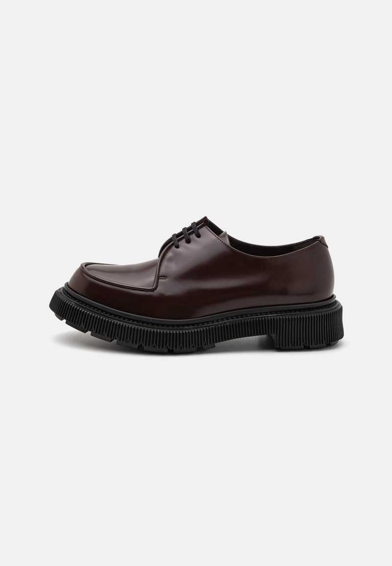 Scarpe in pelle marrone con lacci, punta arrotondata, suola in gomma nera testurizzata e lacci neri sottili, con una finitura liscia e lucida.