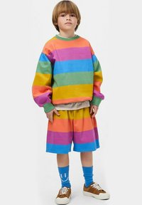 Felpa a righe colorate e pantaloni corti in rosa, blu, verde, arancione e giallo. Presenta una vestibilità comoda, maniche oversize e accessori coordinati.