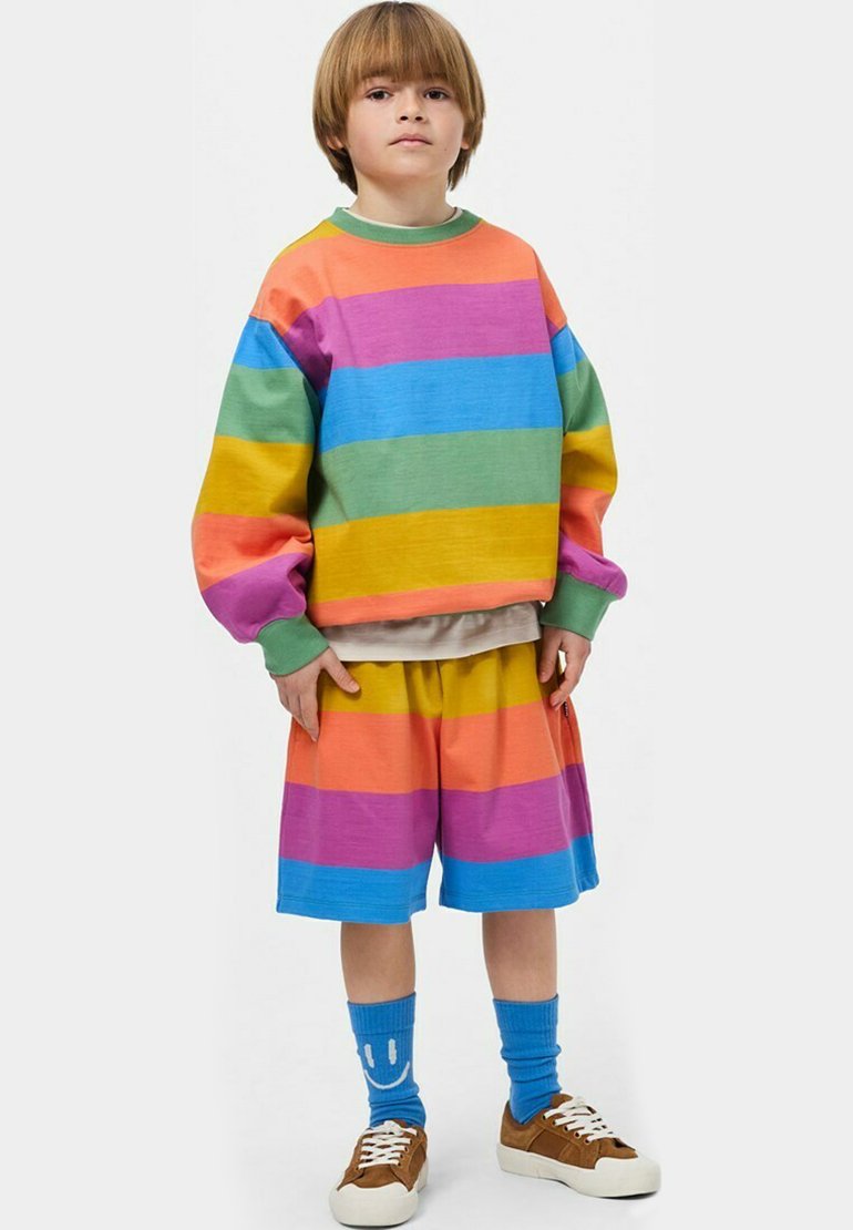 Felpa a righe colorate e pantaloni corti in rosa, blu, verde, arancione e giallo. Presenta una vestibilità comoda, maniche oversize e accessori coordinati.