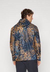 Hooded jack die een gekleurd blauw en bruin abstract patroon heeft, opgebouwd uit textuurmateriaal, en een relaxte pasvorm met lange mouwen.