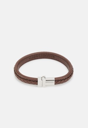 Pulsera de cuero trenzado marrón con un broche metálico plateado grabado con el nombre de la marca "Hilfiger".