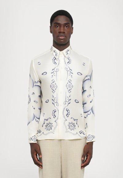 Kreemi siidist nööpide kaudu kinnitatud särk sinise lillemustriga ja kaardus aktsentidega. Omab tavalist kraed ja pikki varrukaid.