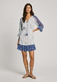 Kurzärmliges Kleid in weiß-blauem Blumenmuster, mit tailliertem Bund und gerafftem Saum. Mit Quasten und durchsichtigen Ärmeln. Aus weichem Stoff.