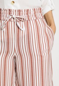 Páskové kalhoty z měkké látky s rustikálním vzorem a bílými pruhy, elastickým pasem a stahovací šňůrkou.