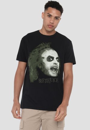 Schwarzes Baumwoll-T-Shirt mit einem grafischen Druck des Gesichts einer Figur, akzentuiert mit grünen Elementen, und dem Text "BEETLEJUICE" in fetter Schrift.