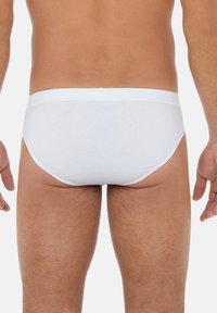 Slip in cotone bianco con una texture liscia e una cintura elastica, caratterizzati da un design semplice senza motivi o accessori aggiuntivi.