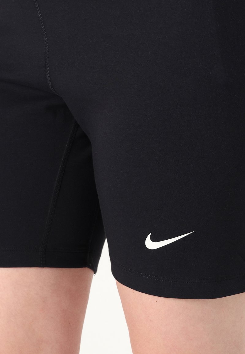 Zwarte sportieve shorts van rekbare stof, met een strakke pasvorm en een wit Nike-logo op de onderste rechterkant.