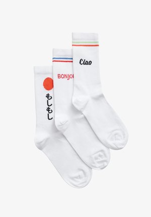 Kolm paari valgeid sokke, igaühel erinevad laused ja kujundused: punane ring, punases "BONJOUR" ja mustas "Ciao" koos värviliste triipudega.