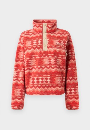 Rød fleecegenser med høy krage, med et geometrisk mønster i nyanser av rød og krem, med en beige knappelist og lomme.