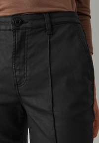 Black pants made of denim, featuring a high waist, straight cut, button closure, and subtle stitching details along the sides.