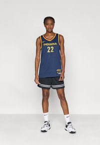 Μπλε ναυτικό μπασκετικό φανελάκι με τη λέξη "INDIANA" σε χρυσά γράμματα, αριθμός 22, συνδυασμένο με μαύρο σορτς με λευκές ρίγες και λευκές κάλτσες.
