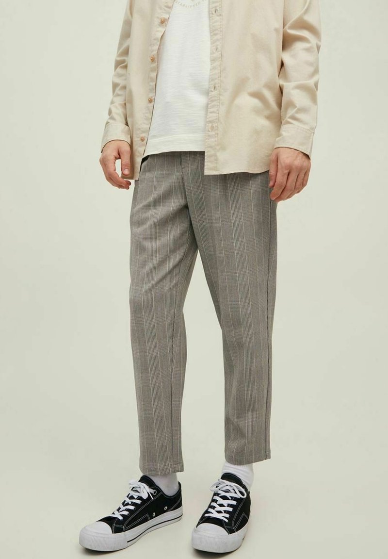 Pantalon à rayures grises coupe slim, en tissu léger, avec poches latérales, porté avec des baskets noires et des chaussettes blanches.