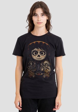 Schwarzes Baumwoll-T-Shirt mit einem grafischen Druck eines Charakters mit einem Totenschädel-Gesicht, umgeben von dekorativen Elementen aus dem Film "Coco."
