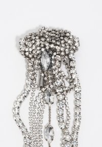 Broszka z cyrkoniami z warstwowymi łańcuszkami, ozdobiona różnymi rozmiarami przejrzystych, błyszczących kamieni osadzonych w srebrnych oprawach, z misternymi detalami.