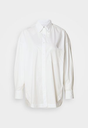 Hvit langermet skjorte med knapper laget av bomull, med en lomme på venstre bryst og en avslappet passform med bølget kant.