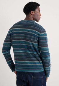 Randig tröja i blå, teal och grå toner. Har rundad hals och långa ärmar med ribbad mudd. Mjuk, texturerad stickad tyg.