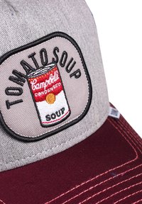 Gray baseball cap with a maroon visor, featuring an embroidered patch of a Campbell's tomato soup can. Text reads "TOMATO SOUP."