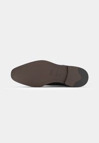 Dark brown leather shoe sole with a smooth surface, featuring a slightly textured heel and rounded toe. Visible brand imprint and stitching.