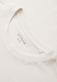 T-shirt blanc à col rond avec coutures visibles et étiquette de taille imprimée "ombre M 48" à l'intérieur du col.