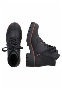 Bottines en cuir noir avec une semelle en caoutchouc épaisse, bout rond, laçage sur le devant, fermeture éclair latérale et détail décoratif sur la tirette de la fermeture.