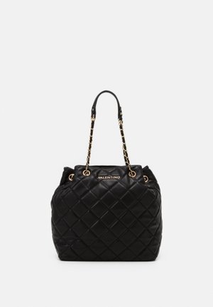 Borsa a tracolla in pelle trapuntata nera con hardware dorato, dotata di manici doppi e un logo prominente sul davanti. Finitura morbida e texturizzata.