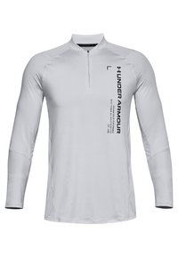 Valkoinen pitkähihainen urheiluetiketti, jossa on neljännesvetoketju ja pystysuora musta Under Armour -logo sekä teksti oikealla puolella rintaa.