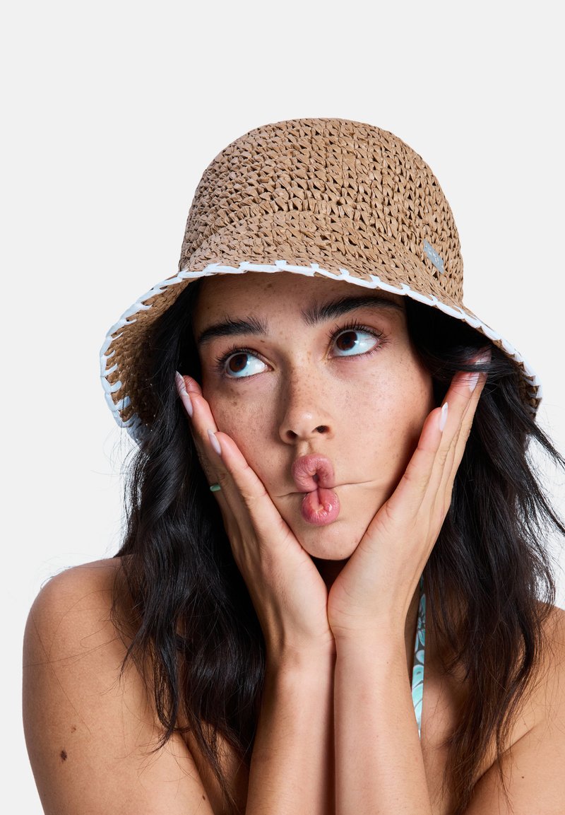 Καφέ υφαντό καπέλο τύπου κουβά με λευκή επένδυση, με υφασματικό σχέδιο. Διακριτικές λεπτομέρειες ραφής και μικρό λογότυπο στο πλάι.