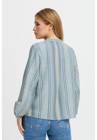 Camicia a maniche lunghe azzurro chiaro con strisce verticali in blu scuro e giallo. Tessuto morbido con un motivo sottile. Visualizzazione da dietro.