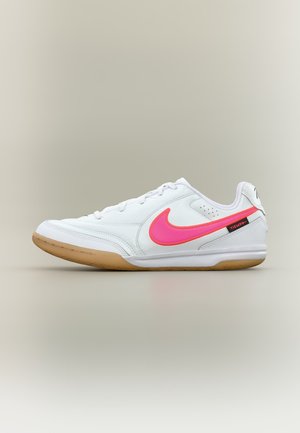Chaussure de football d'intérieur Nike Tiempo blanche à coupe basse avec un swoosh rose vif et une semelle en gomme, vue de côté sur fond neutre.