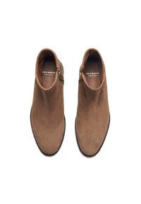 Bottes chelsea en suède marron avec une texture lisse, fermeture éclair latérale et bout arrondi. Présente une marque intérieure "FRED MARTIN MADE IN SPAIN."