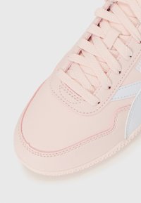 Sneaker rosa chiaro con lacci abbinati e striscia laterale bianca, che mostra i dettagli delle cuciture frontali e laterali su uno sfondo bianco.