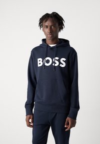 Sweatshirt azul-marinho com capuz ajustável e bolso frontal, apresentando letras grandes em branco "BOSS" no peito. Textura de tecido suave.